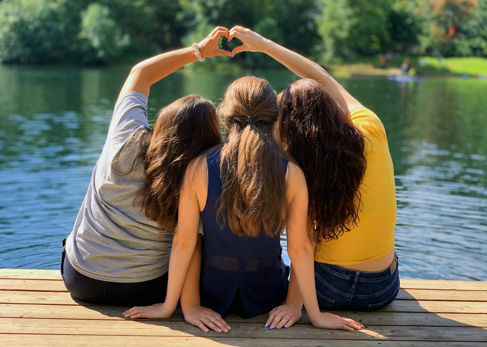 3 loving sisters sitting on the dock in the daytime