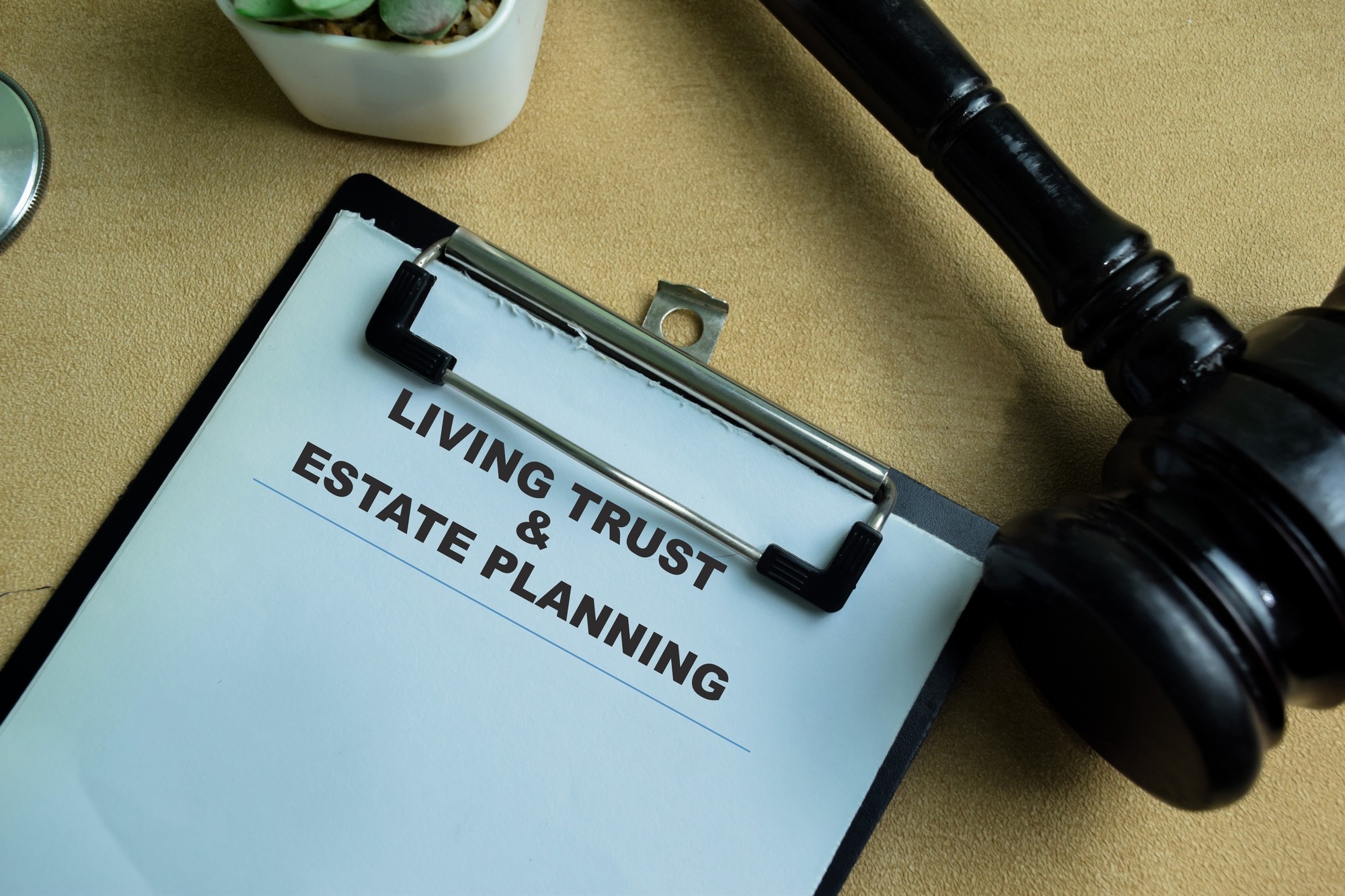 Clipboard displaying 'Living Trust & Estate Planning' alongside a gavel, symbolizing legal processes related to estate management.